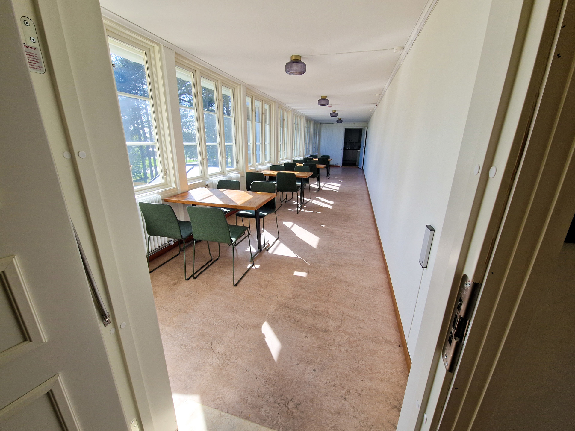 Lång korridor med mycket ljusinsläpp från fönster på vänster sida