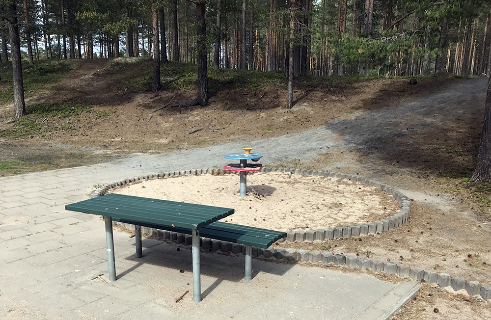 Rund sandlåda med litet lekbord. Sittbänk bredvid