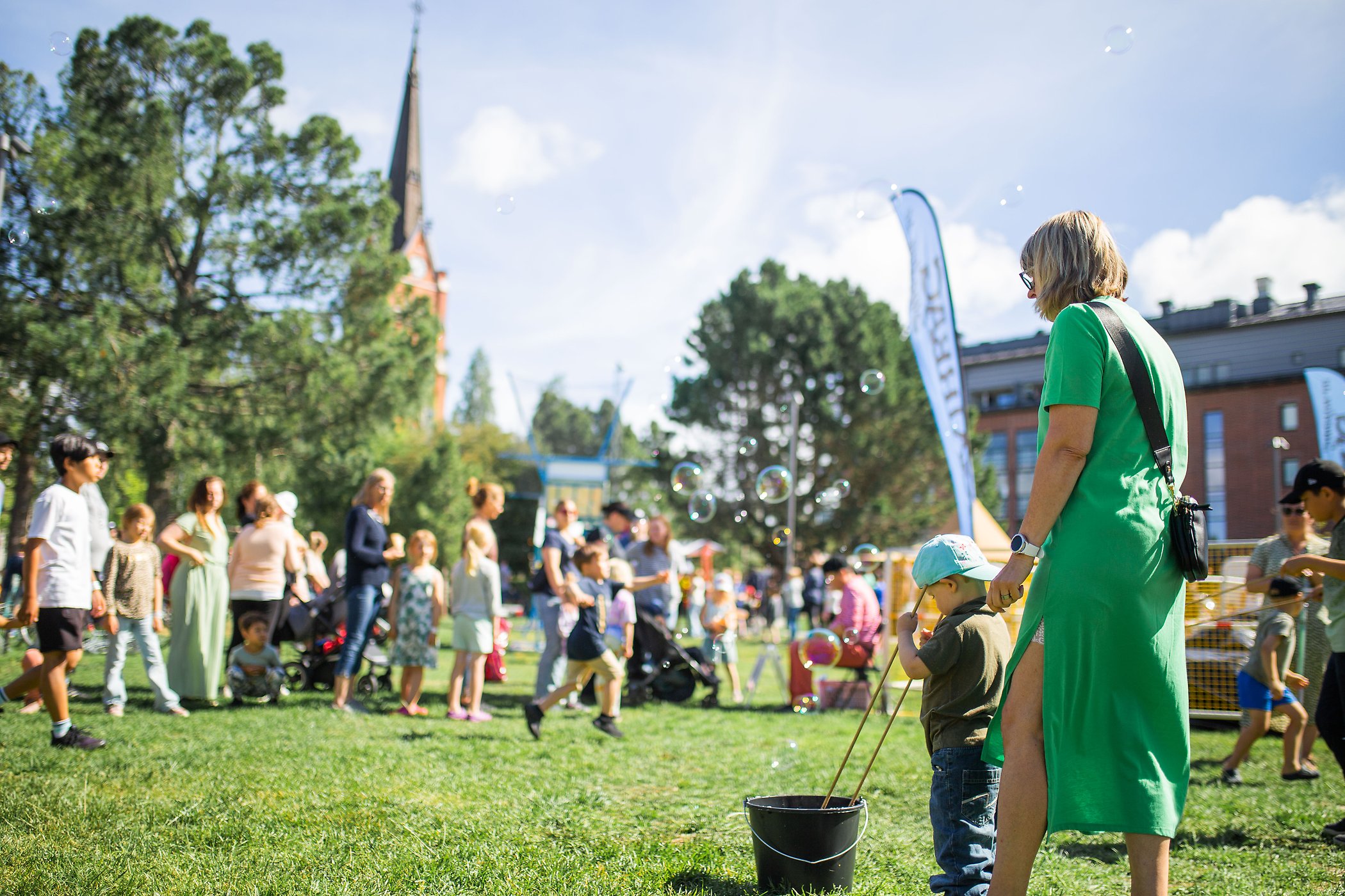 Barn som leker med såpbubblor i Stadsparken med Luleå domkyrka i bakgrund